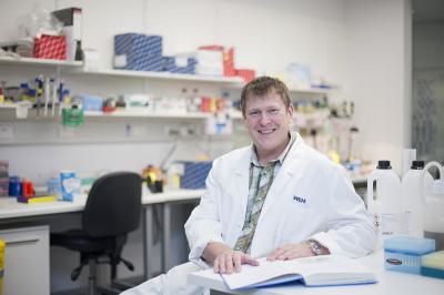 Dr. Lukasz Kedzierski sits smiling in his office