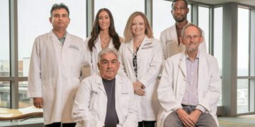 research team gathers in front of a window