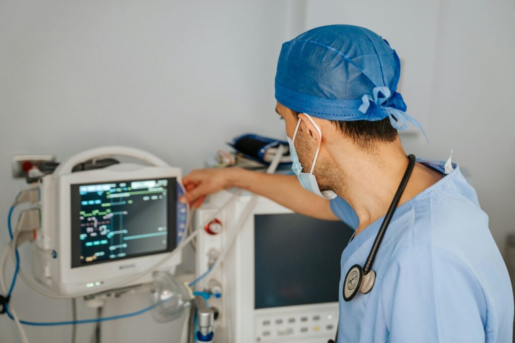 a healthcare worker, wearing a medical mask, monitors vitals