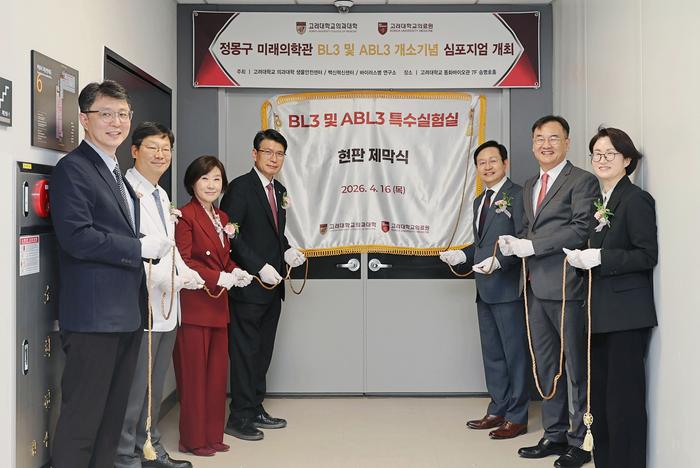 South Korea’s Largest University Biosafety Labs Open With Pandemic Preparedness in Mind officials, wearing white gloves, stand on either side of a silk banner announcing the opening of the high containment lab.
